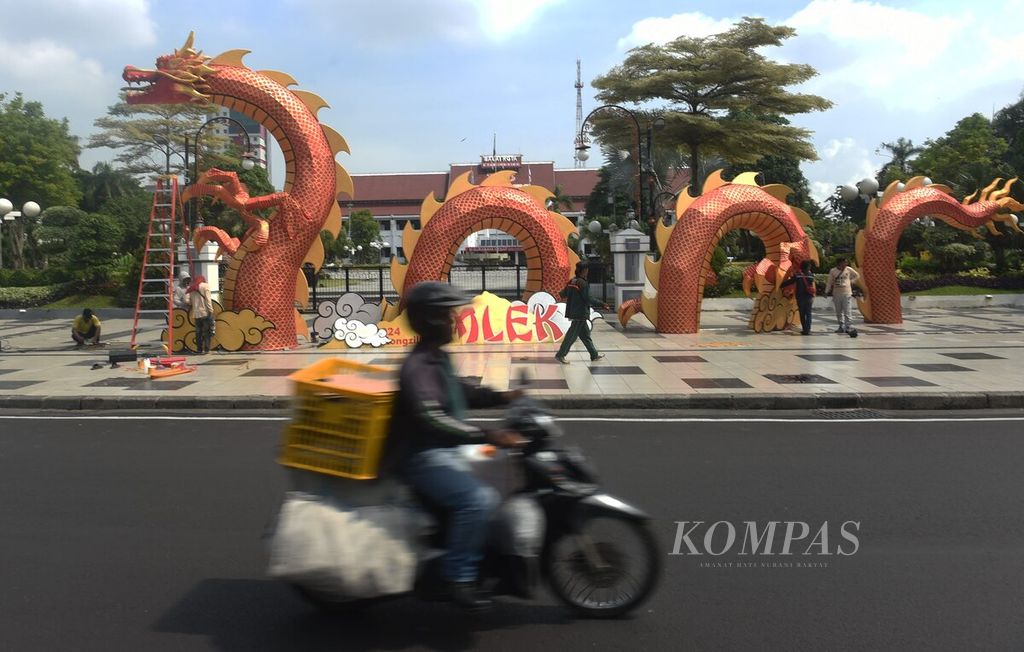 Pengendara melintasi hiasan berbentuk naga raksasa dalam rangka Imlek 2024 di depan Balai Kota Surabaya, Kamis (1/2/2024).