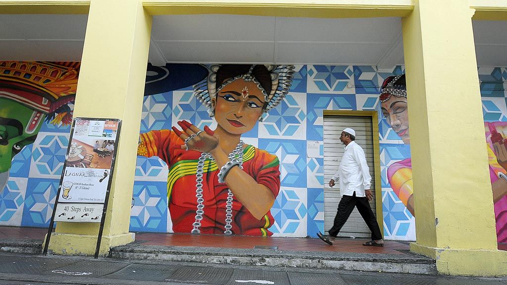 warga melintas dengan latar belakang mural yang terpampang di salah satu bangunan di Little India Singapura, Jumat (26/1). Kawasan Little India menjadi salah satu proyek seni yang dikerjakan oleh mahasiswa dan alumnus Lasalle. Karya-karya ini menjadi bagian dari Singapore Art Week.