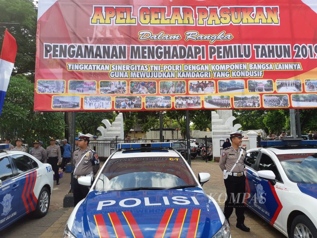 Beberapa polisi bersiaga di samping mobil patroli di sela Apel Gelar Pasukan dalam rangka Pengamanan Menghadapi Pemilu Tahun 2019 di Serang, Banten, Jumat (22/3/2019).