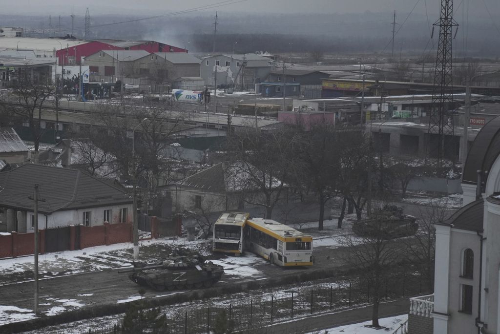 Tank-tank tentara Rusia bergerak melintasi sebuah ruas jalan di pinggiran Mariupol, Ukraina, Jumat (11/3/2022). 