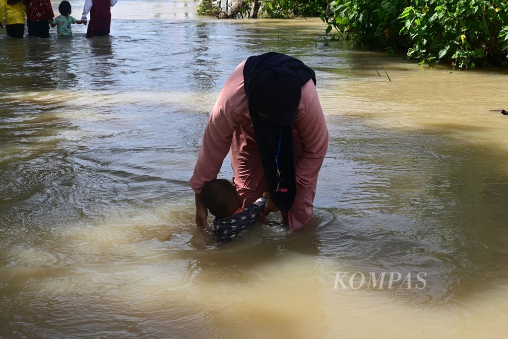 Anak-anak bermain di genangan banjir di wilayah Desa Pantai Harapan Jaya, Muara Gembong, Kabupaten Bekasi, Jawa Barat, Jumat (3/3/2023). Banjir berasal dari luapan Sungai Ciherang.
