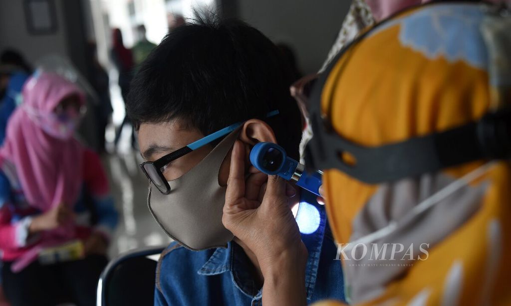 Petugas medis memeriksa kondisi telinga siswa SLB B Karya Mulia saat acara ”Peduli Pendengaran untuk Semua” , Surabaya, Jawa Timur, Rabu (24/2/2021). Kegiiatan ini diselenggarakan oleh PERHATI KL Jatim Utara dalam rangka menyambut World Hearing Day pada 3 Maret. Pemeriksaan telinga diikuti oleh 22 siswa. 