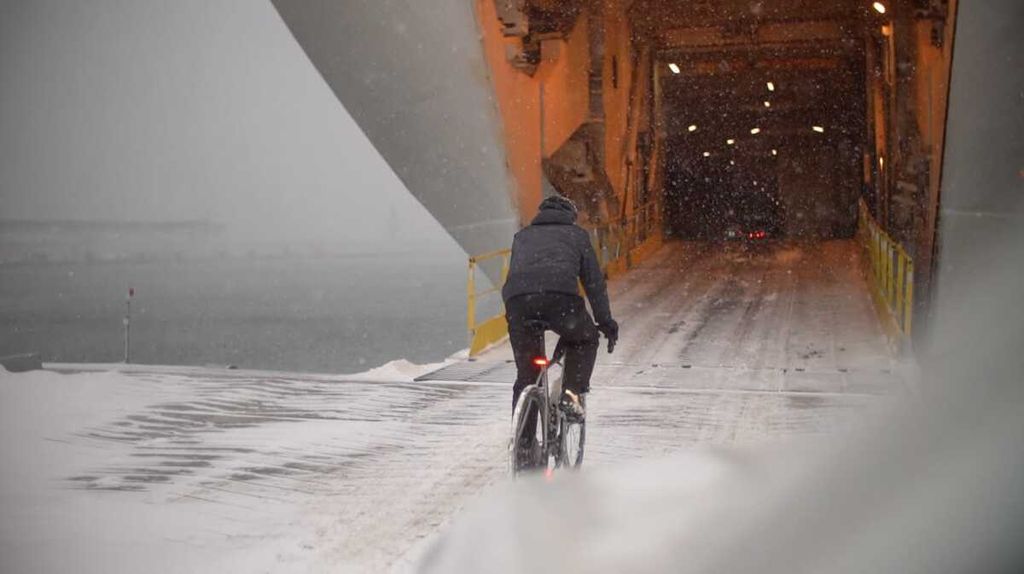 Royke Lumowa bersepeda menaiki kapal penyeberangan di Pelabuhan Tallinn, Estonia. Ia hendak ke Helsinki, Finlandia. Salju menutupi pelabuhan dan kapal.