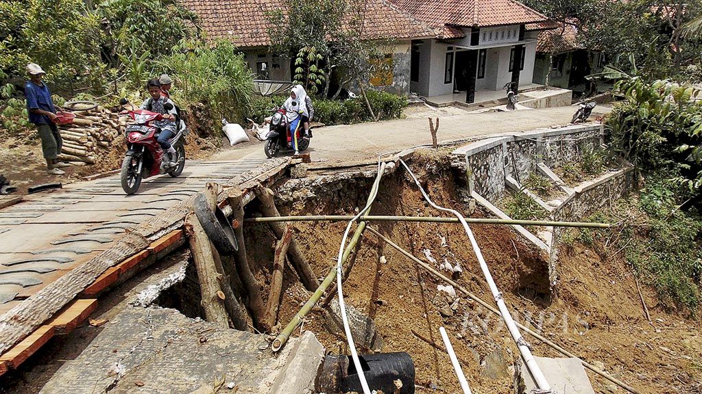 Warga melintasi jembatan darurat di Dusun Cimahi, Desa Gunungmanik, Kecamatan Ciniru, Kabupaten Kuningan, Jawa Barat, Kamis (1/3). Lebih dari 1.000 warga  Ciniru terpaksa mengungsi dalam sepekan terakhir setelah  permukiman mereka dilanda tanah bergerak dan longsor.
