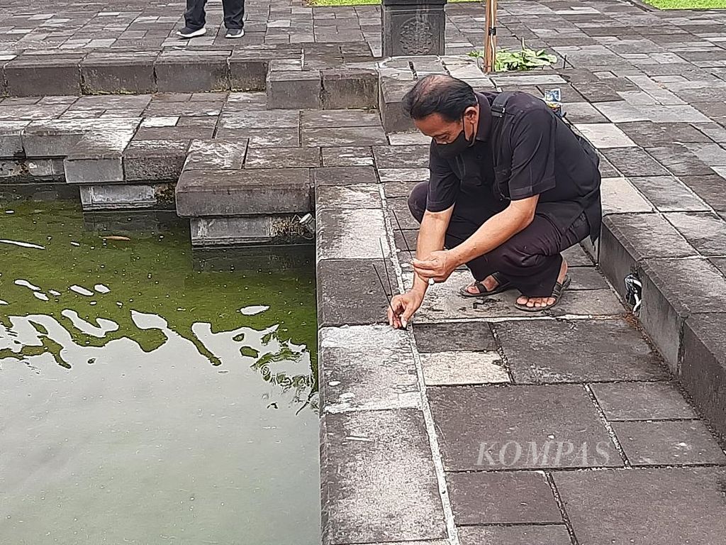 Agus Sumadyo (63), salah seorang pawang hujan asal Kecamatan Borobudur, Kabupaten Magelang, menancapkan hio di depan kolam kecil di Hotel Manohara di kompleks Taman Wisata Candi Borobudur, Kabupaten Magelang, Jawa Tengah, Jumat (25/3/2022).
