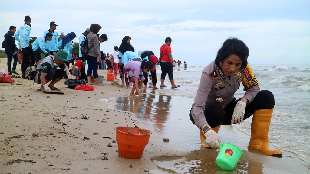 Balikpapan Police deputy chief Comr. Yolanda (right) and other participants clean the coast around Kilang Mandiri Beach in Balikpapan, East Kalimantan, on Wednesday (4/4). Local people and government officials are cleaning the resort beach in the city to revive the Balikpapan coastline contaminated by the oil spill.