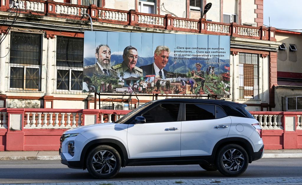 Sebuah mobil keluaran terbaru melintas di depan poster mendiang pemimpin Kuba Fidel Castro, mantan presiden Raul Castro, dan Presiden Miguel Diaz-Canel di Havana, Kuba, Kamis (5/9/2024). Di tengah krisis ekonomi yang parah di Kuba, mobil-mobil kelas atas mulai mencuri perhatian, dari mobil klasik Amerika Serikat tahun 1950-an hingga mobil kompak Lada dan Moskvich Soviet. 