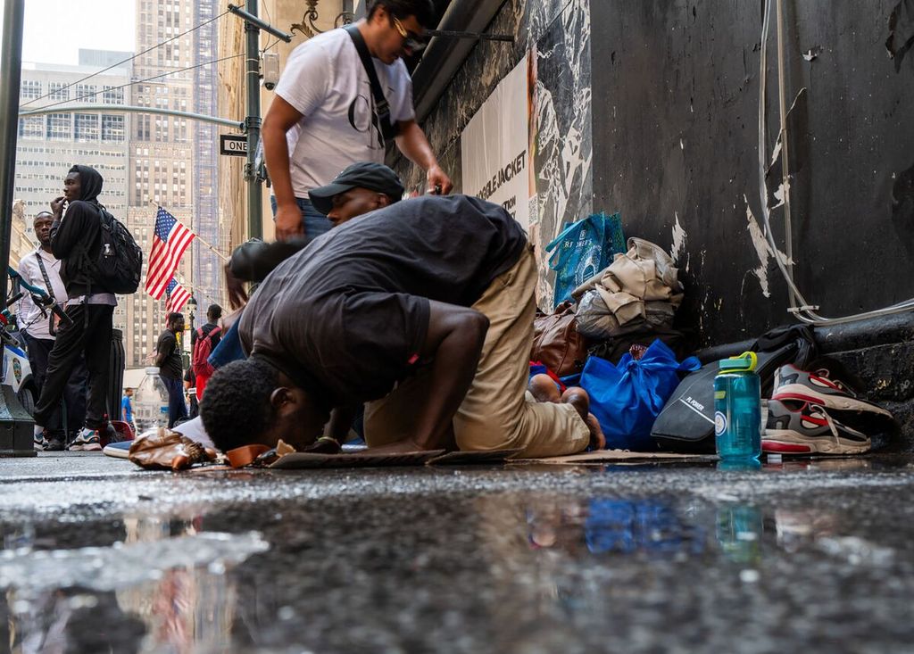 Seorang Muslim menunaikan shalat saat menunggu bersama ratusan migran lain di depan Hotel Roosevelt, New York City, AS, 31 Juli 2023. 
