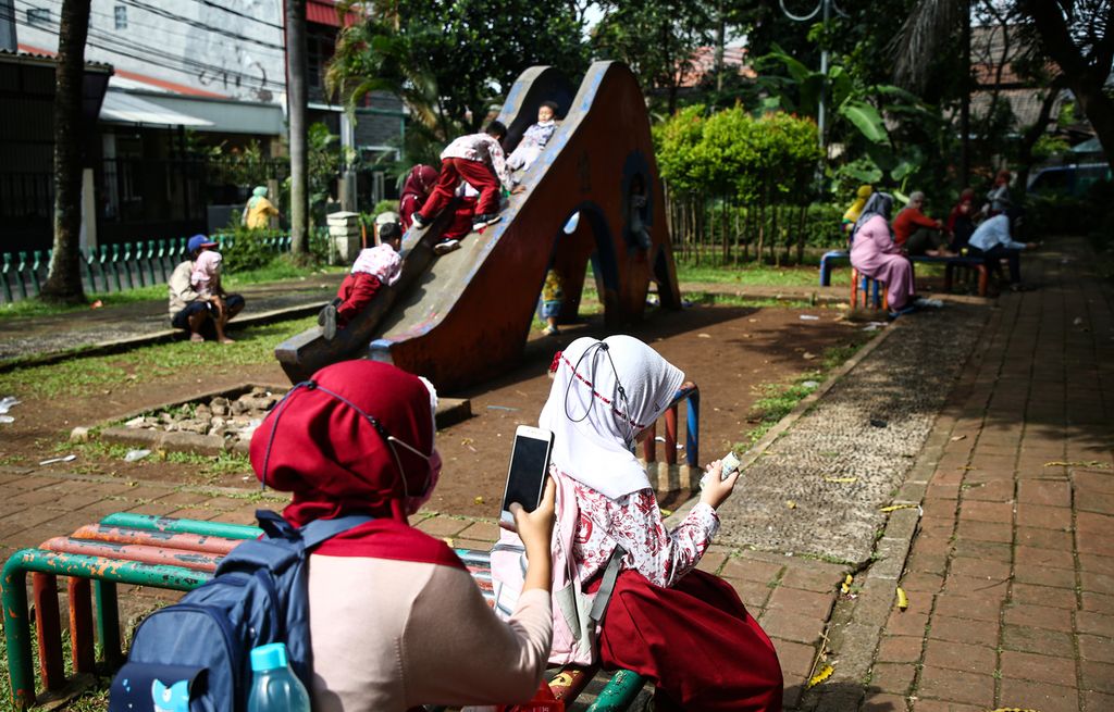 Orangtua menemani anaknya bermain di taman seusai sekolah di kawasan Joglo, Kembangan, Jakarta Barat, Kamis (27/1/2021). Dibutuhkan peran aktif orangtua dalam mengawasi anak mereka saat pulang sekolah di masa pandemi ini.