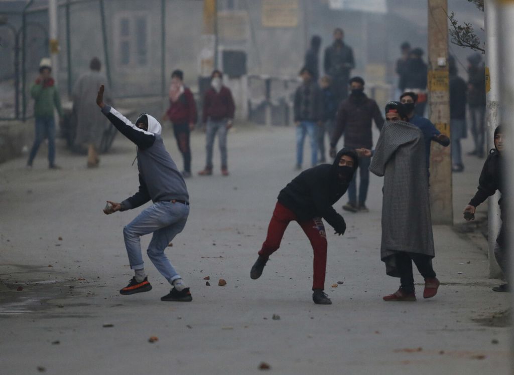 Para demonstran di Kashmir, wilayah yang dipersengketakan oleh India dan Pakistan, melempar batu ke arah polisi India di Srinagar, India, Senin (17/12/2018). Tentara bersenjata dan polisi menyebar di sebagian besar wilayah Kashmir yang dikuasai India untuk menghentikan protes anti-India dan meredam seruan separatis berunjuk rasa di markas militer India di Kashmir.