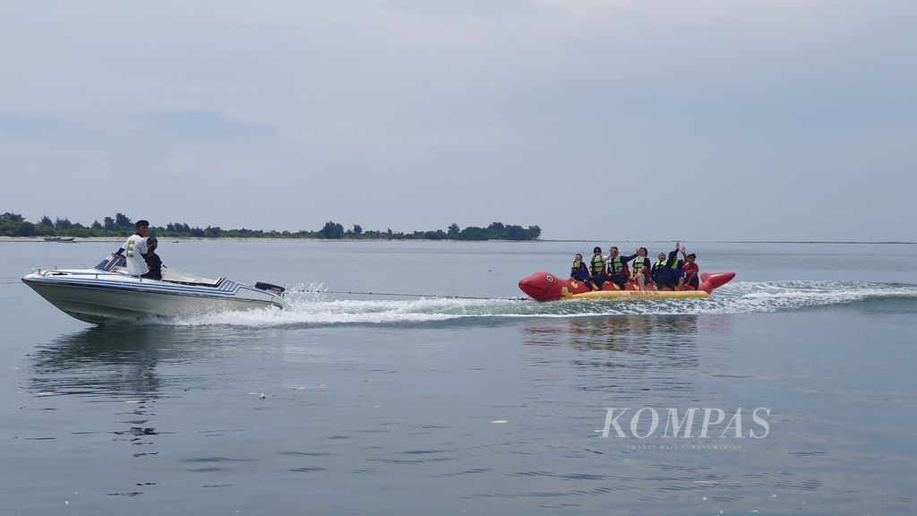 Wisatawan tengah bermain olahraga air banana boat di Pulau Pari, Kabupaten Kepulauan Seribu, Jakarta, Minggu (14/4/2024).
