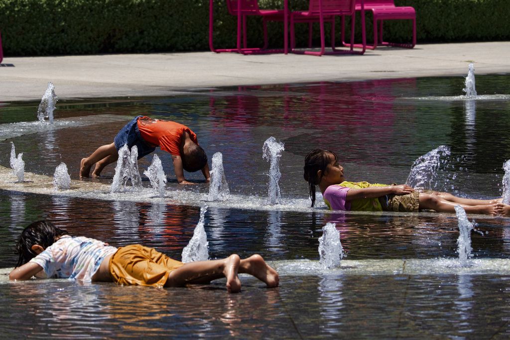 Anak-anak mendinginkan diri dengan membasahi badan mereka dengan air di sebuah lokasi air mancur di kota Los Angeles, Amerika Serikat, Minggu (16/7/2023). Suhu udara di beberapa negara bagian AS akan meningkat dalam beberapa waktu ke depan.