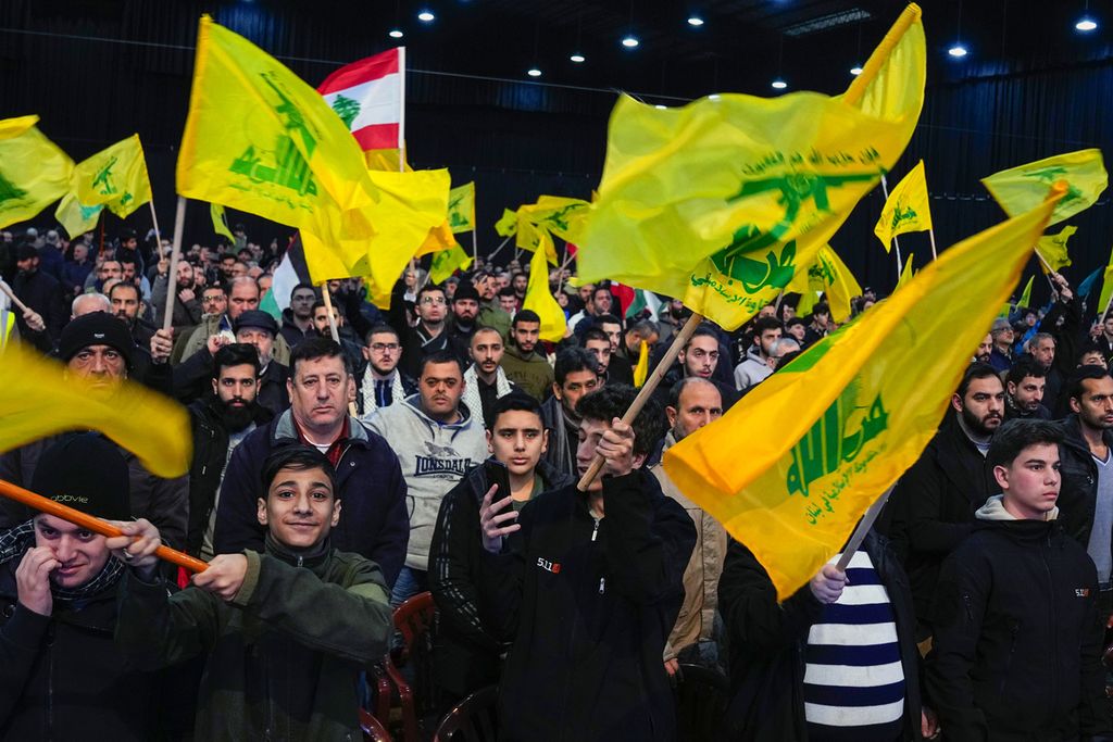 Pendukung Hezbollah melambaikan bendera saat mendengarkan pidato pemimpin Hezbollah Sayyed Hassan Nasrallah pada peringatan kematian para pemimpin Hezbollah, Jumat (16/2/2024). 