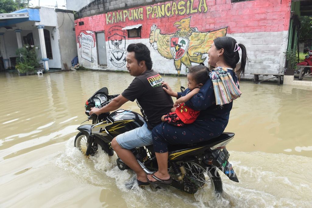 Pengendara melewati jalan desa yang dilanda banjir Kali Lamong, Desa Driyorejo, Kecamatan Driyorejo, Kabupaten Gresik, Jawa Timur, Rabu (22/2/2023).