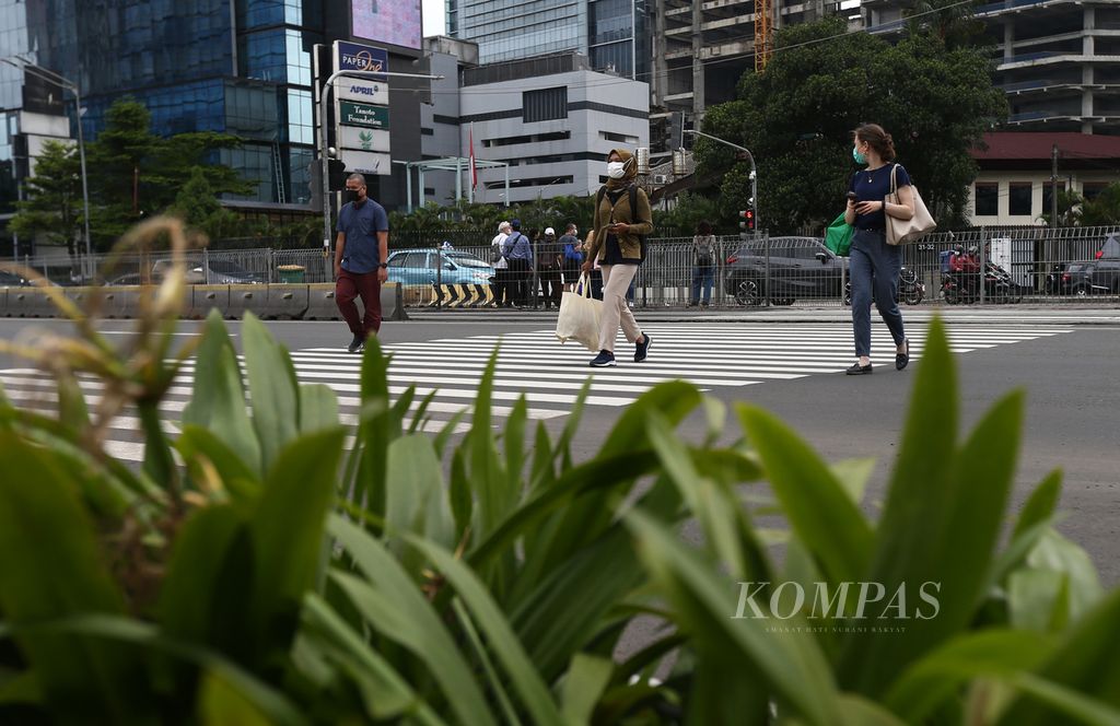 Warga menyeberang jalan protokol di Jalan Jenderal Sudirman, Jakarta, Selasa (1/3/2022). Dengan mengacu pada sejumlah data, pemerintah mempersiapkan transisi dari pandemi menuju endemi. Masyarakat juga perlu mendapat edukasi yang memadai.