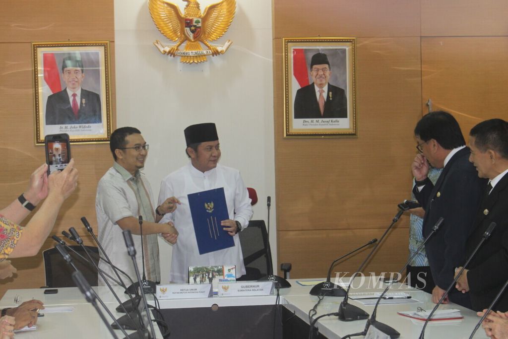 Gubernur Sumatera Selatan Herman Deru (kanan) dan Ketua Umum Ikatan Motor Indonesia (IMI) Pusat Sadikin Aksa, memperlihatkan nota kesepahaman penyelenggaraan Motocross Grand Prix (MXGP) di Palembang, Senin (27/5/2019). 