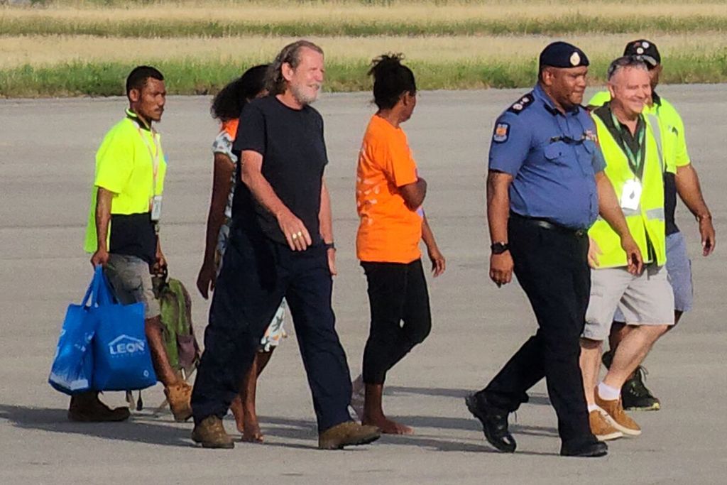 Bryce Barker (ketiga dari kiri), yang disandera selama sepekan oleh kelompok bersenjata di sebuah dataran tinggi, dikawal menuju pesawat pascapembebasan dirinya di Port Moresby, Papua Niugini, Minggu (26/2/2023). 