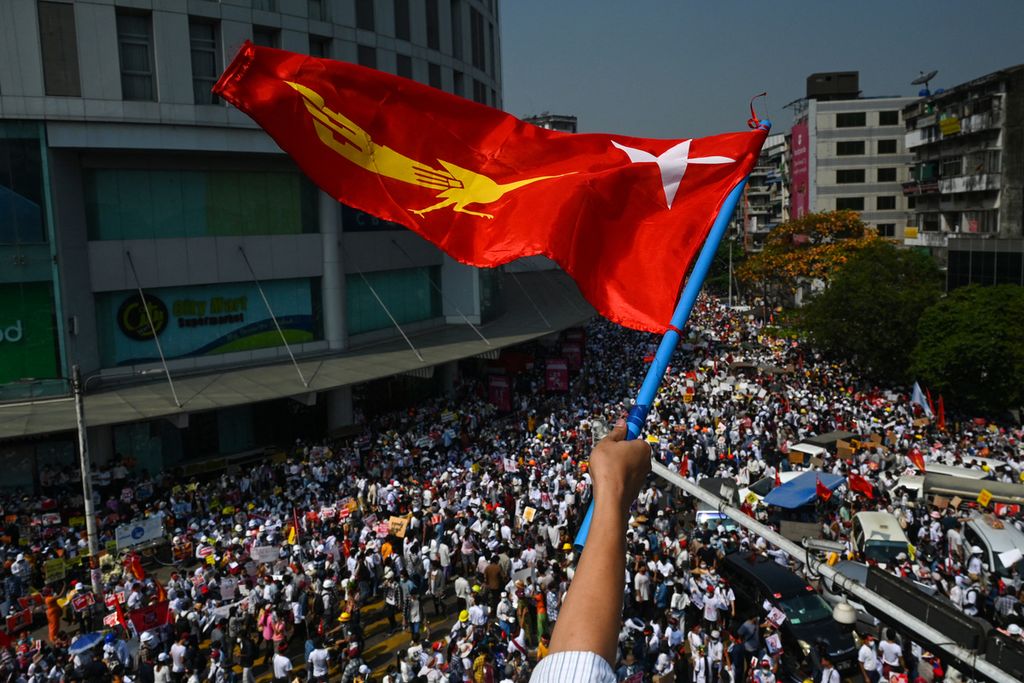 Bendera Liga Nasional untuk Demokrasi (NLD) dikibarkan seorang pengunjuk rasa saat mengikuti demonstrasi menentang kudeta militer di Yangon, Senin (22/2/2021). Kudeta Myanmar terjadi sejak 1 Februari 2021. 