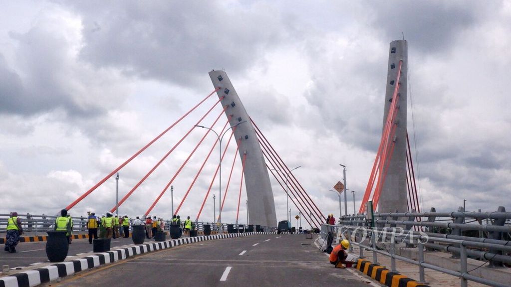 Pekerja mengecat trotoar Jembatan Sei Alalak di Kota Banjarmasin, Kalimantan Selatan, 13 September 2021. Biaya pembangunan jembatan lengkung<i> cable stayed</i> pertama di Indonesia ini lebih dari Rp 278 miliar.