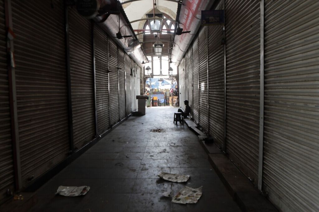 Dalam arsip foto pada 24 Maret 2020, seorang pria duduk di luar kompleks kios yang tutup di Mumbai,India. Pemulihan perekonomian tahun 2022 masih menemui jalan terjal akibat pandemi Covid-19, inflasi, dan lonjakan harga.  