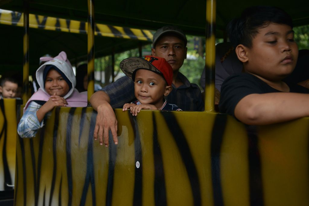 Warga menaiki kereta keliling saat berlibur di Kebun Binatang Ragunan, Jakarta Selatan, Minggu (25/12/2022). Libur Natal dimanfaatkan sejumlah warga untuk berlibur di tempat-tempat wisata, salah satunya di Kebun Binatang Ragunan. Sebanyak 76.000 warga memadati Kebun Binatang Ragunan. Jumlah tersebut meningkat sebanyak 39.000 dibandingkan pada Sabtu (24/12/2022) atau H-1 Natal. 