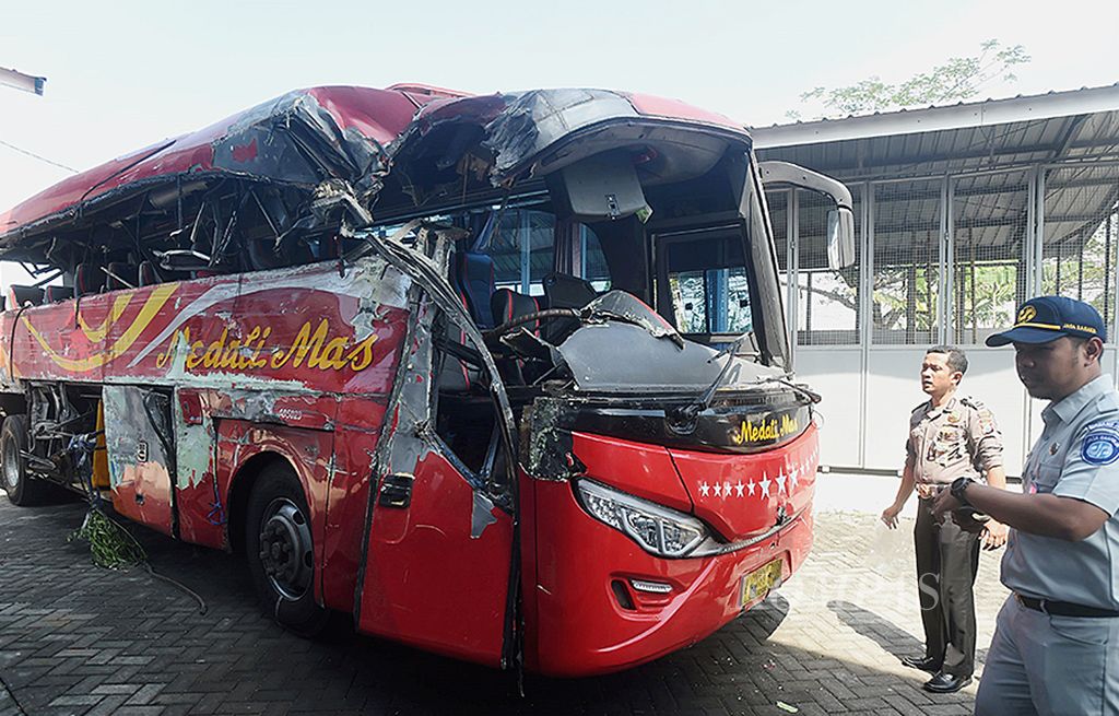 Petugas memeriksa bus PO Medali Mas yang diamankan di Rumah Penyimpanan Benda Sitaan Klas 2 Probolinggo setelah terlibat kecelakaan dengan truk, Probolinggo, Jumat (14/7). Kecelakaan di tikungan Pantai Bentar, Kabupaten Probolinggo,  antara bis trayek Denpasar-Malang itu dan truk mengakibatkan 10 penumpang tewas.