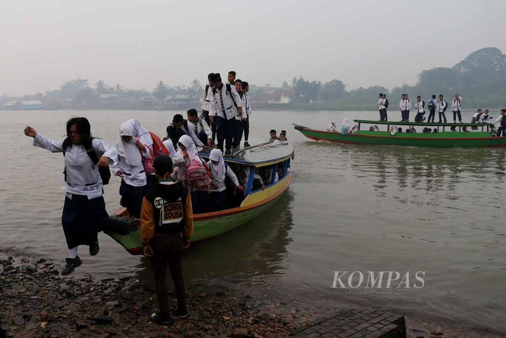 Sejumlah siswa berangkat ke sekolah menggunakan getek saat melintasi Sungai Musi, Kota Palembang, Sumatera Selatan, yang masih diselimuti kabut asap, Jumat (18/9/2015), pukul 06.47 WIB.