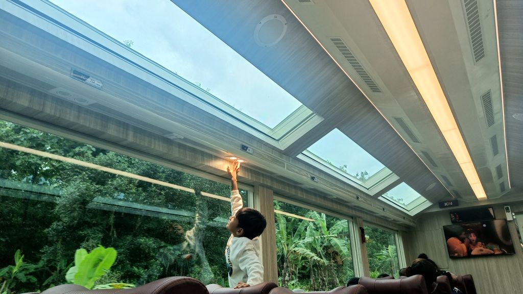 Seorang anak menghidupkan lampu baca pada siang hari di kereta panoramic saat perjalanan dari Stasiun Gambir menuju Stasiun Yogyakarta, Kamis (29/12/2022).