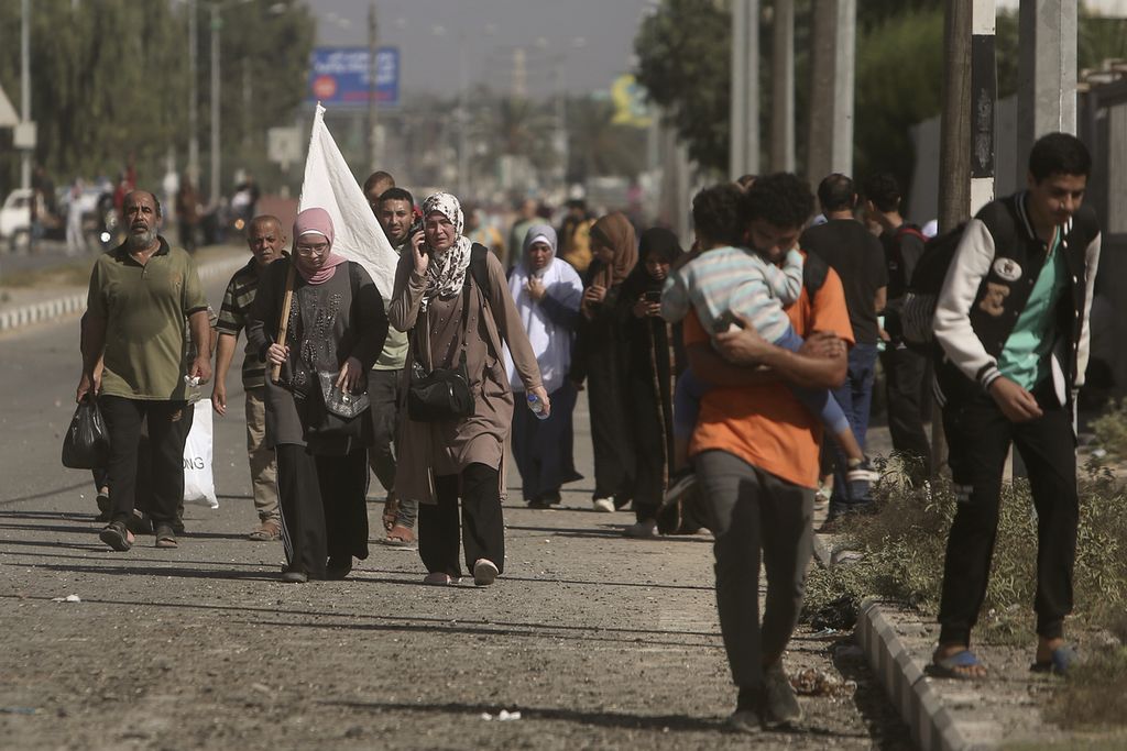 Seorang perempuan warga Gaza berjalan di Jalan Salah al-Din, Gaza, sambil membawa bendera putih sepanjang perjalanan dari Gaza utara menuju Gaza selatan, Selasa (7/11/2023). Meski dinyatakann sebagai tempat berlindung, wilayah Gaza selatan masih terus dibombardir oleh militer Israel. 
