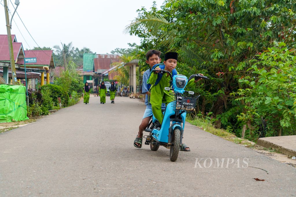 Anak-anak di desa Tebat Patah, Kecamatan Taman Rajo, Kabupaten Muaro Jambi, Jambi, Jumat (7/6/2024), sudah terbiasa menggunakan sepeda listrik untuk keperluaan sehari-hari. 