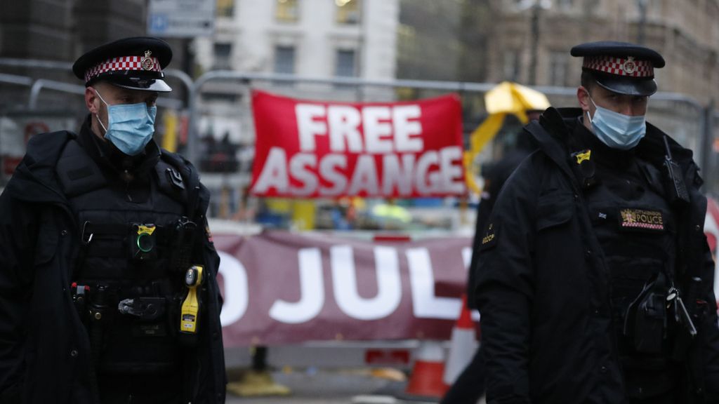 Polisi berjaga di dekat spanduk pendukung Julian Assange di luar Old Bailey, London, tempat berlangsungnya sidang ekstradisi atas Julian Assange ke Amerika Serikat, Senin (4/01/2021). Assange didakwa berdasarkan Undang-Undang Spionase AS tahun 1917 karena "secara tidak sah memperoleh dan mengungkapkan dokumen rahasia yang terkait dengan pertahanan nasional". AP/Frank Augstein