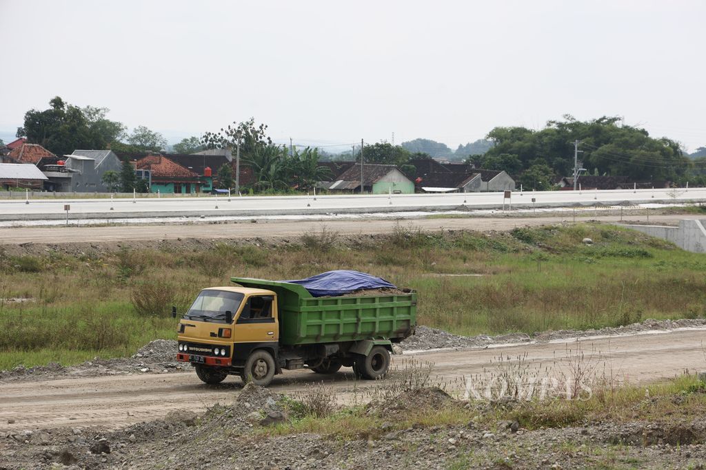 Truk pengangkut material melintas di lokasi pembangunan jalan tol ruas Kartasura-Klaten di Kecamatan Banyudono, Boyolali, Jawa Tengah, Senin (20/3/2023). Sekitar 6 kilometer dari simpang tol Kartasura ke arah Klaten ditargetkan dapat digunakan secara fungsional sebagai jalur Lebaran 2023 untuk mengurangi kemacetan di sekitar kawasan simpang Kartasura. Ruas tol Kartasura-Klaten sepanjang 22,3 km itu merupakan bagian dari PSN Jalan Tol Surakarta-Yogyakarta-Kulon Progo untuk meningkatkan konektivitas dan mengurai kemacetan di Jawa Tengah dan Yogyakarta.
