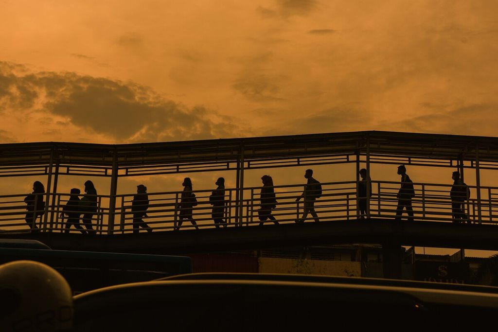 Potret mobilitas pekerja saat pengujung senja di jembatan penyeberangan Halte Bus Transjakarta, Harmoni, Jakarta, Kamis (30/12/2021). Memasuki akhir tahun 2021, pemerintah kembali mengingatkan masyarakat untuk meningkatkan kewaspadaan dengan mengurangi mobilitas akibat ditemukannya transmisi lokal dari varian Omicron. 
