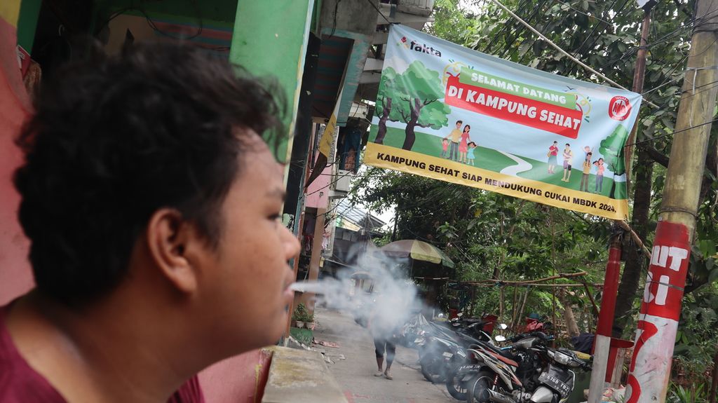 Seorang warga merokok di Kampung Tanpa Rokok Penas Tanggul di Kelurahan Cipinang Besar Selatan, Kecamatan Jatinegara, Jakarta Timur, Selasa (24/10/2023) siang.