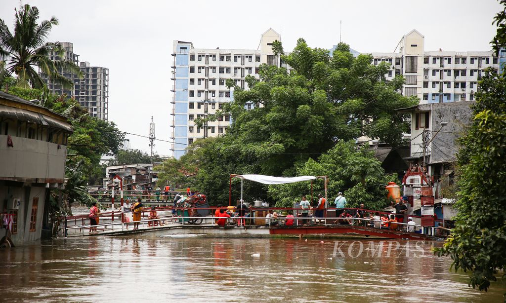 Warga mengungsi di atas jembatan di kelurahan Karet Tengsin, Tanah Abang, Jakarta Pusat, Selasa (25/2/2020). Banjir akibat curah hujan yang tinggi ini tidak hanya merendam kawasan pemukiman namun juga memutus akses jalan di sejumlah wilayah di Jakarta, Bekasi, dan Tangerang.