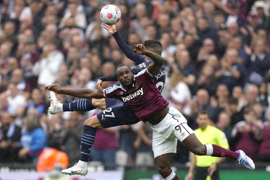 Pemain West Ham Michail Antonio (depan) berebut bola dengan pemain Manchester City Joao Cancelo pada laga Liga Inggris di Stadion London, Minggu (15/5/2022). Laga berakhir imbang 2-2. 