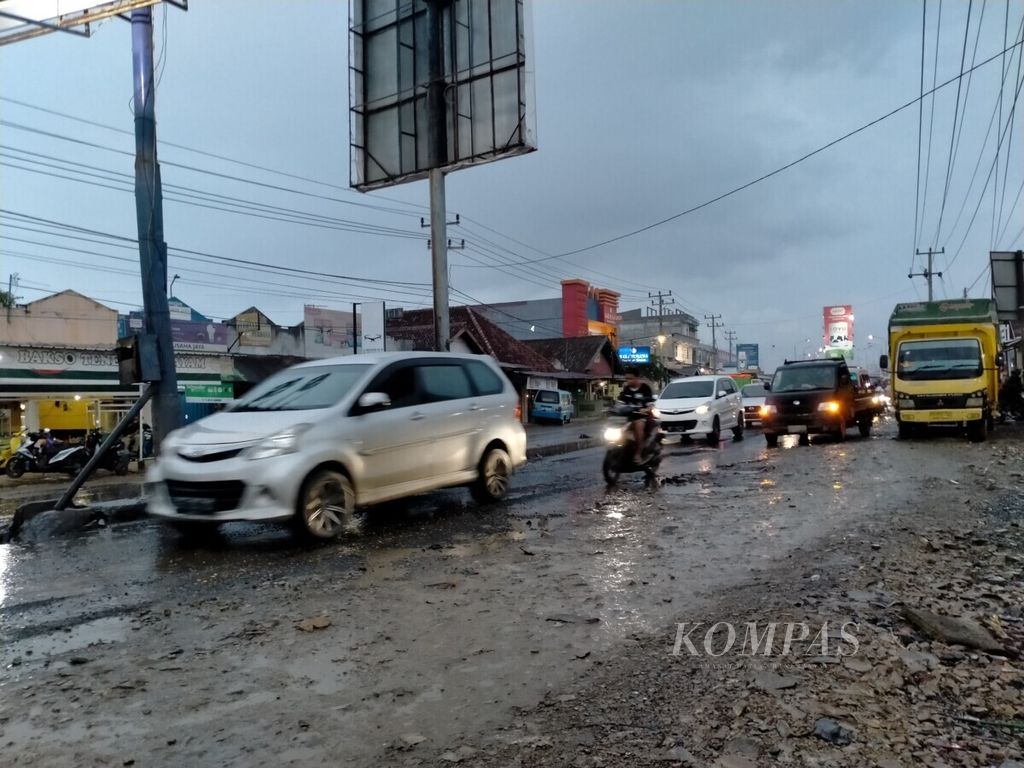 Kondisi jalan lintas Sumatera di Kecamatan Natar, Kabupaten Lampung Selatan, Lampung, rusak akibat sering tergenang air hujan, Rabu (29/1/2020).