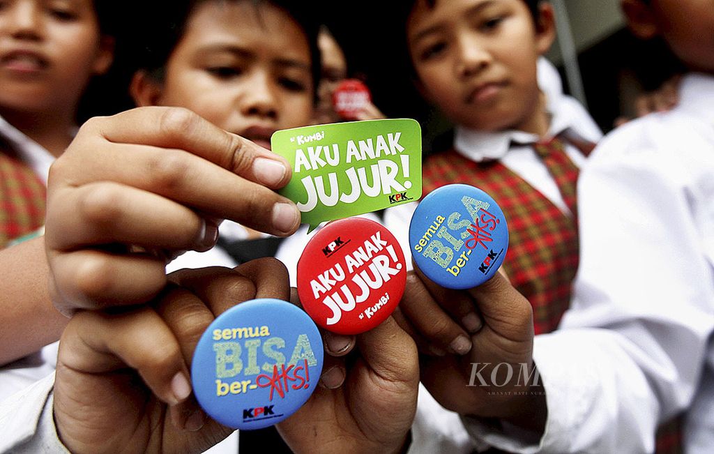 Sejumlah siswa SD Negeri Andir Kidul, Kota Bandung, Jawa Barat, menunjukkan pin dan stiker saat sosialisasi antikorupsi di sekolahnya, Senin (12/10/2015).  