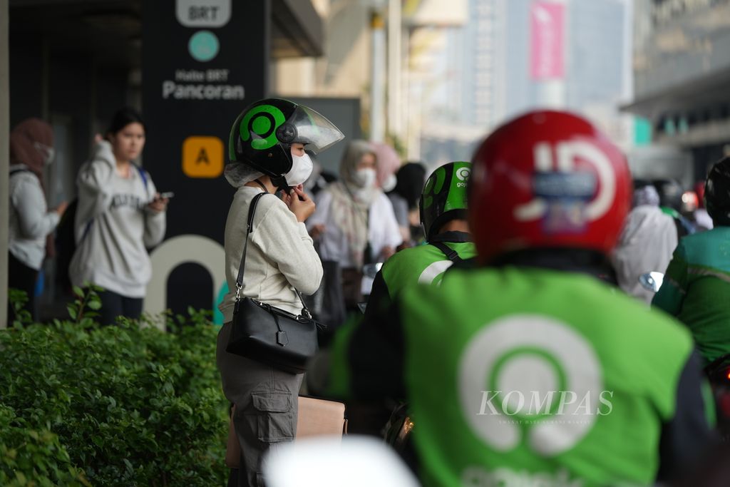 Pengguna jasa ojek daring bersiap naik sepeda motor di Pancoran, Jakarta Selatan, Kamis (29/8/2024). 