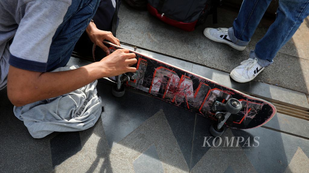 Pemain <i>skateboard </i>memperbaiki roda di sela-sela waktu bermain di trotoar Jalan Jenderal Sudirman-Thamrin, Jakarta, Jumat (12/3/2021).