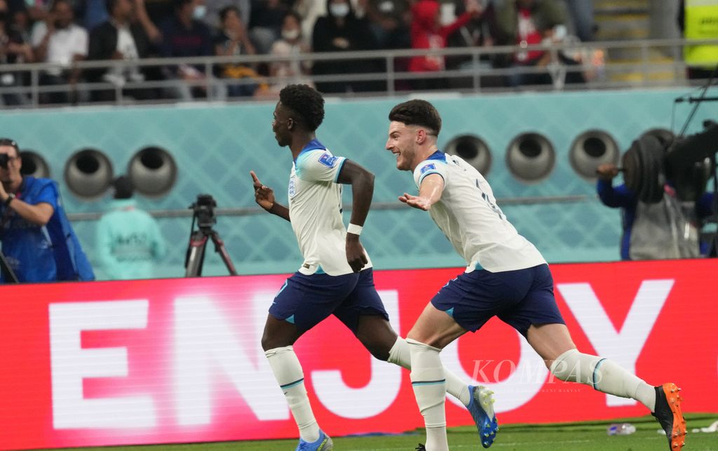 Pemain Inggris, Bukayo Saka (depan), merayakan gol yang dicetaknya ke gawang Iran di penyisihan Grup B Piala Dunia 2022 di Stadion Khalifa, Qatar, Senin (21/11/2022). Inggris menang 6-2 atas Iran. 