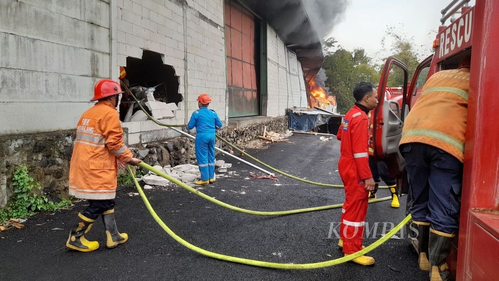 Petugas pemadam kebakaran membobol dinding untuk memadamkan api yang membakar gudang pabrik kertas di Pandanlandung, Wagir, Kabupaten Malang, Jawa Timur, Jumat (16/9/2022)
