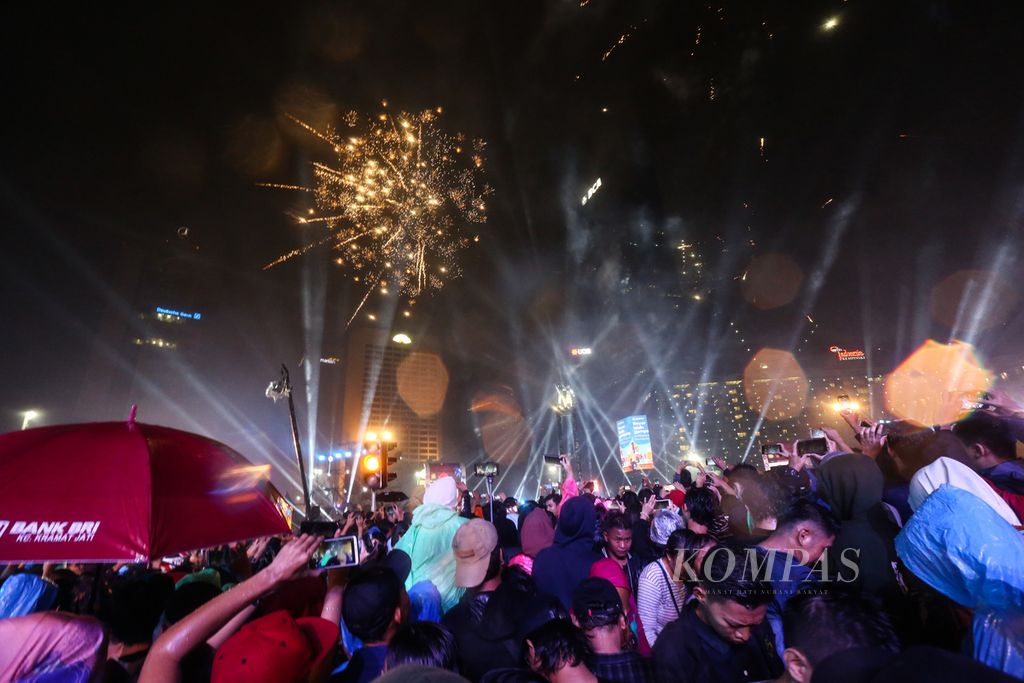 Warga tumpah ruah di kawasan Bundaran Hotel Indonesia, Jakarta Pusat, untuk merayakan malam pergantian tahun, Selasa (31/12/2019). Hujan yang mengguyur sejak sore tak menyurutkan niat warga untuk menyaksikan konser musik dan kembang api dalam rangka memeriahkan Tahun Baru.