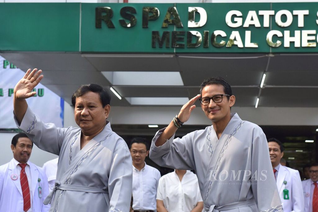 Bakal calon presiden dan wakil presiden Pilpres 2019 Prabowo Subianto dan Sandiaga Uno (kanan) menyapa jurnalis saat menjalani tes kesehatan di RSPAD, Jakarta, Senin (13/8/2018). 