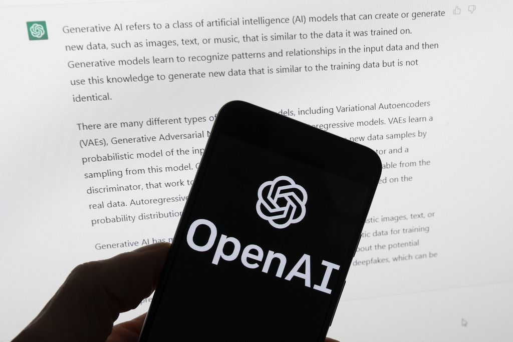 Logo OpenAI tampak di sebuah telepon seluler di depan layar komputer yang menayangkan output dari program kecerdasan buatan ChatGPT, ketika difoto pada 21 Maret 2023, di Boston, AS.