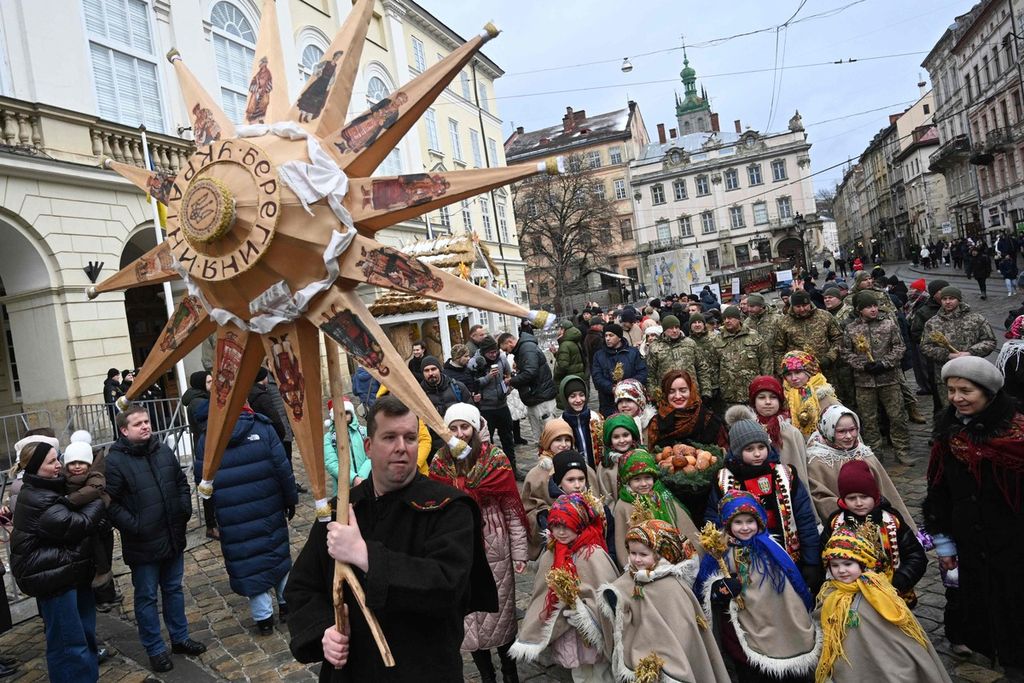 Warga berpawai di jalan saat merayakan malam Natal di Lviv, Ukraina barat, Minggu (24/12/2023). 