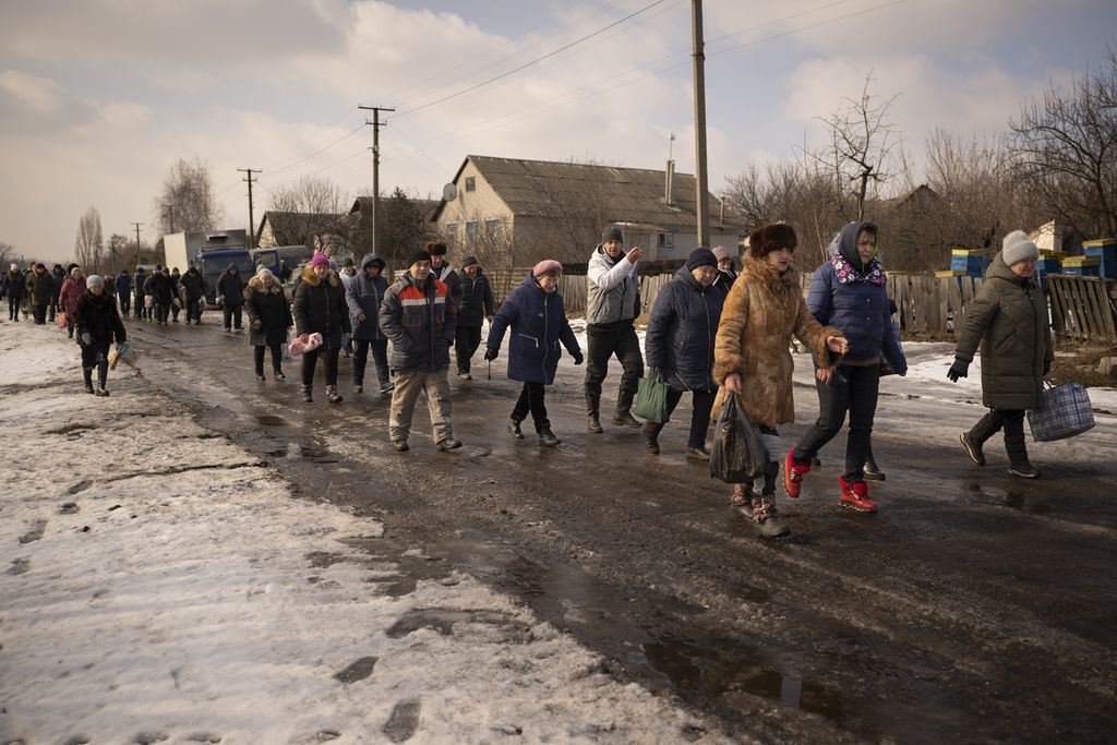 Warga desa berjalan untuk mengantre bantuan kemanusiaan dan pemeriksaan medis di klinik keliling di Desa Nechvolodivka, Ukraina, Rabu (22/2/2023). Sukarelawan untuk Aliansi Kesehatan Masyarakat, organisasi perawatan kesehatan Ukraina, mendirikan klinik perawatan keliling ke daerah-daerah yang baru saja dibebaskan di Ukraina timur.