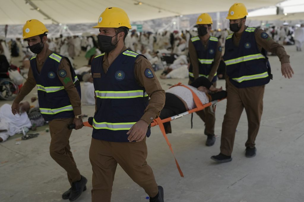 Empat petugas medis menandu seorang anggota jemaah yang mengalami gangguan kesehatan akibat sengatan panas matahari di Mina, Mekkah, Arab Saudi, Minggu (16/6/2024). 