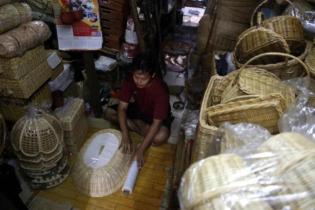 Gunawan membungkus tudung saji rotan pesanan pelanggan di bengkel kerjanya di kawasan Grogol, Jakarta Barat, Selasa (26/9/2023). Gunawan mengatakan, sejak ia membuka lapak di lokapasar pada 2020, ada saja barang dagangannya yang terjual setiap hari. Saat penjualan secara langsung (luring) sepi, berdagang melalui lokapasar sangat membantu.  