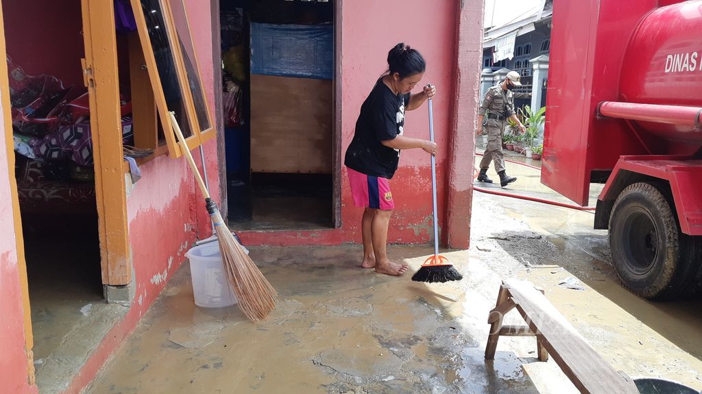 Rini (38), warga Kelurahan Ujuna, Kecamatan Palu Barat, Kota Palu, Sulawesi Tengah, membersihkan rumahnya dari air bercampur lumpur pada Rabu (7/9/2022). Air sudah surut di permukiman warga yang dilanda banjir pada Selasa (6/9/2022).
